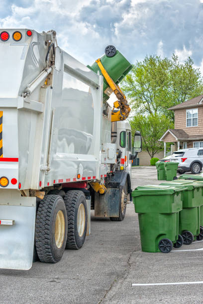 Garbage Truck With Robotic Arm Collections Trash Vertical shot of a garbage truck with a robot arm dumping trash from a residential green plastic trash can. garbage truck arm stock pictures, royalty-free photos & images