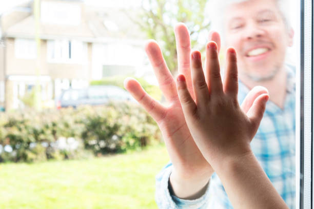 istock Father and son`s hands separated by glass 1219434002