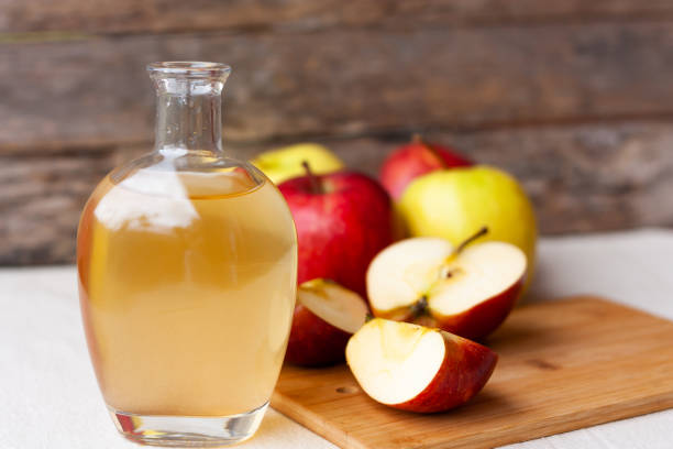 ガラスピッチャーと熟した新鮮な赤と黄色のリンゴの木製の背景にアップルの有機酢。健康的なオーガニック食品のコンセプト。 - juice carafe glass decanter ストックフォトと画像