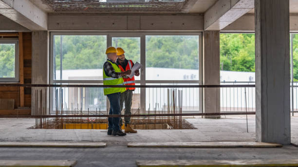 istock Two men talking and looking at a blueprint at a construction site 1219437888