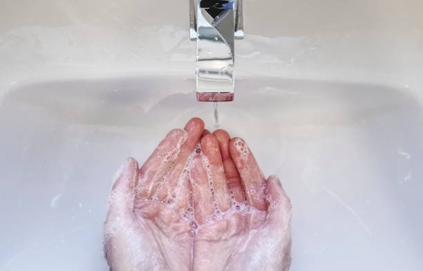 istock Soapy wet hands washing with blue anti-bacterial soap under tap 1219438226