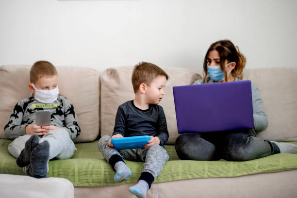 istock Family at home sofa with mask and tablet pc in quarantine isolation 1219440471