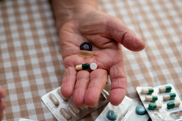 woman holds a lot of medicine in her hand - vitamin pill picking up pill capsule imagens e fotografias de stock