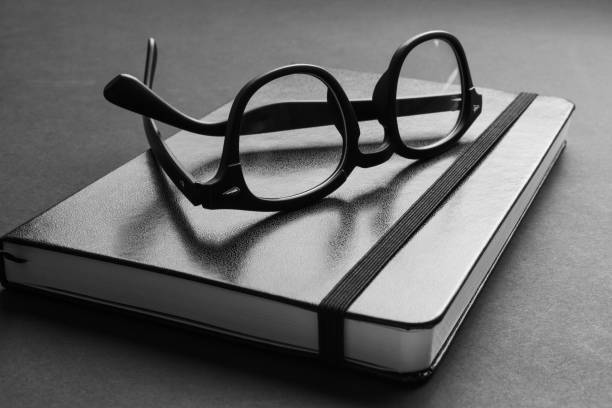 istock Closeup view of trendy black eyeglasses on trendy notebook. 1219441880