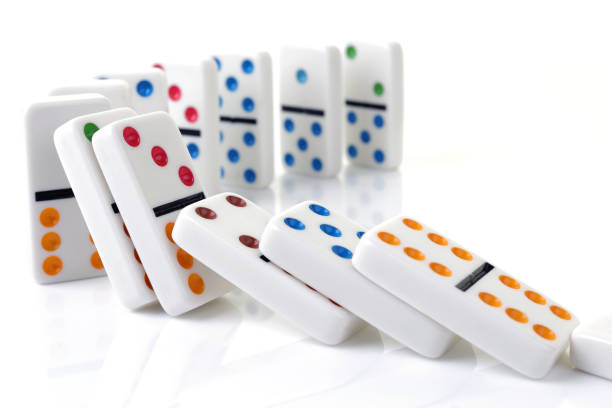 Falling colorful dominoes on a white surface A line of falling colorful dominoes on a white surface domino photos stock pictures, royalty-free photos & images