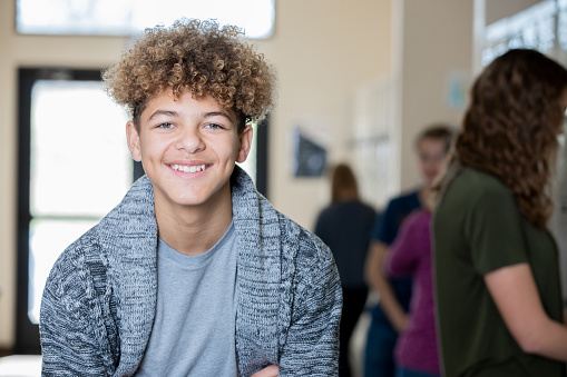 Male high school student smiles in high school hallway