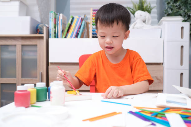 asian 3 years old toddler boy enjoy using glue doing arts at home, fun paper and glue crafts for toddlers, children's art project - 2 3 years fotos imagens e fotografias de stock