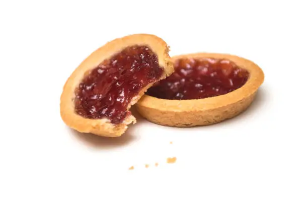 Closeup of two crunched mini tartlets with strawberry jam on white background