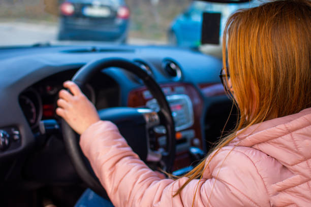 istock girl sitting behind the car wheal 1219445265