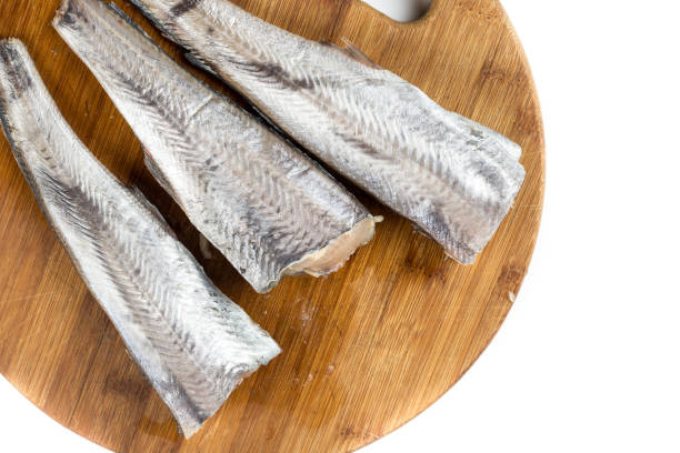 istock Flat lay hake fish on the wooden board with white background copy space 1219445663