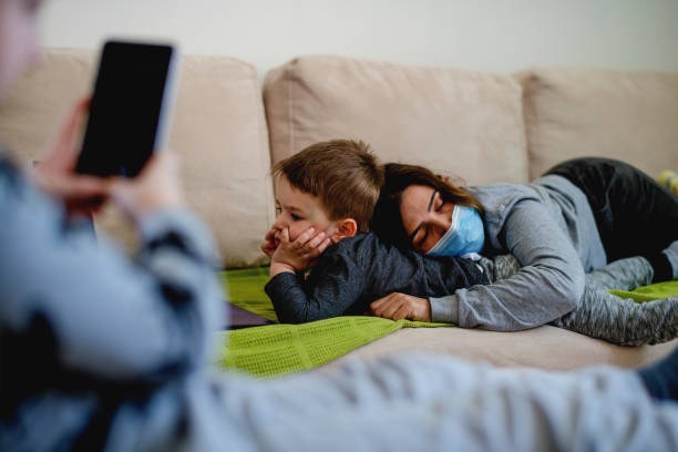 istock Mother and sons at home sofa with mask using technology at quarantine isolation 1219448365