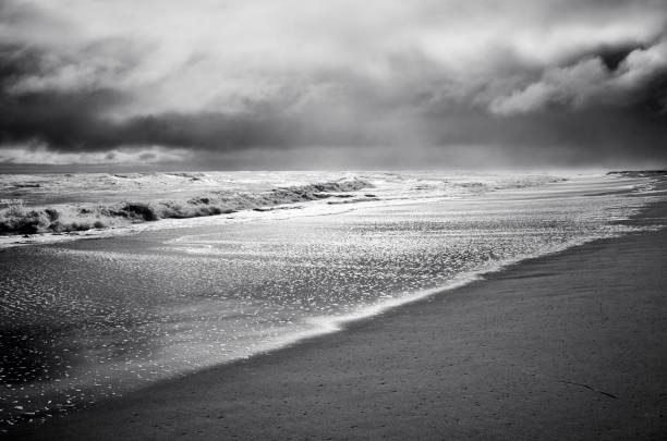 Stormy sea, beach and clouds at dark dramatic. Sunlight, back lit Stormy sea, beach and clouds at dark dramatic. Sunlight, back lit black and white beach stock pictures, royalty-free photos & images