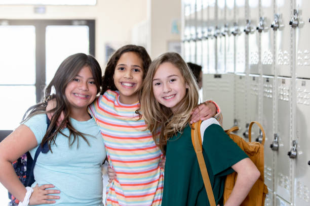 istock Group of three female students smiling with their arms around each other 1219451066