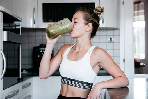 Beautiful young and fit woman having a blended fruit for breakfast