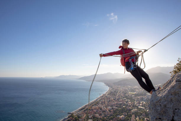 young woman rappels from rock climb summit - mountain climbing rock climbing motivation awe photos et images de collection