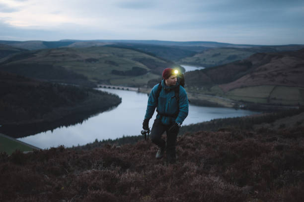 istock Man hikes with headlamp through rugged mountainous landscape 1219453036
