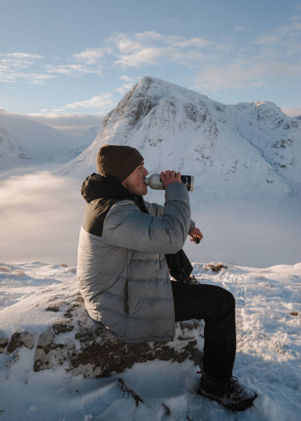 istock Man drinks water on snowy mountain ridge at sunrise 1219453175