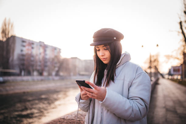 istock Smiling girl walking by the river and using her phone 1219455696