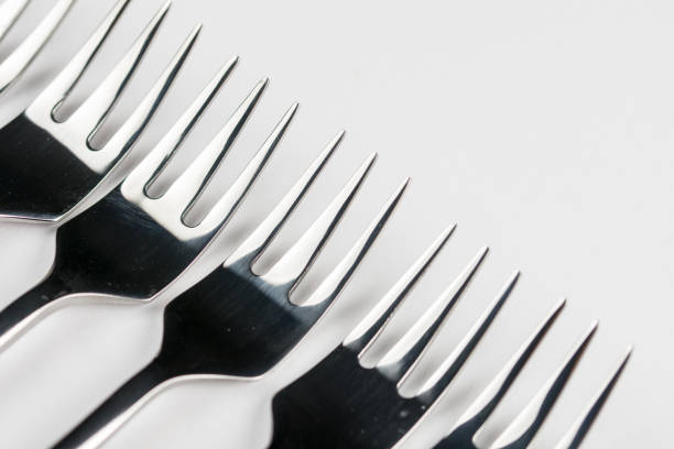 istock Selective focus closeup macro metal shiny forks lined up over white background 1219456715