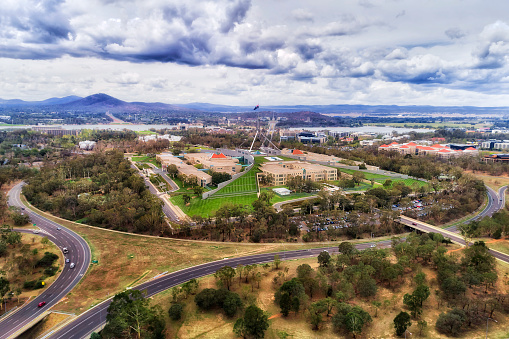 The capital hill in Canberra with Federal parliament house overlooking lake Burley Griffin in scenic aerial view.