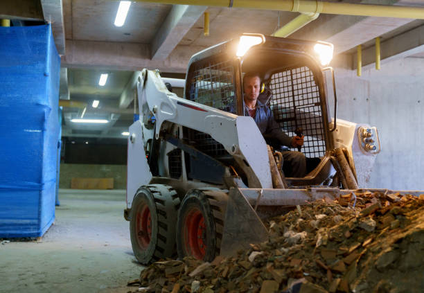 Latin american blue collar worker operating a mini excavator removing concrete waste at a construction site - Industry concepts