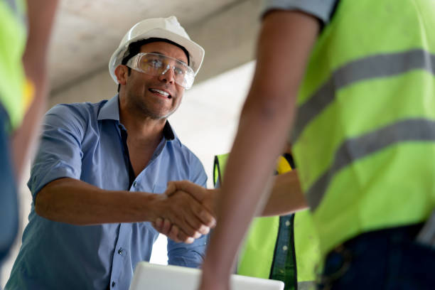 alegre arquitect apretón de manos de un contratista de construcción en una obra de construcción - hardhat construction men handshake fotografías e imágenes de stock