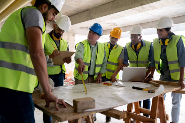 istock Senior architect during a meeting with team of professionals at a construction site pointing with a measuring tape while addressing his team 1219457534