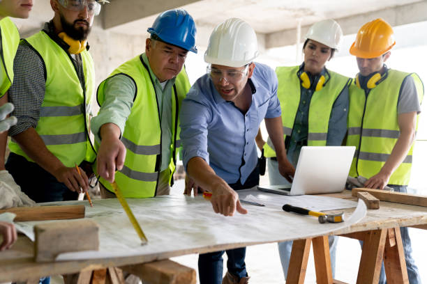 istock Confident supervisor addressing team of architects and engineers while pointing at a blueprint in a construction site 1219457543