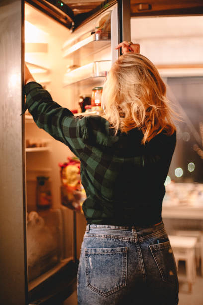 Young woman looking in open refrigerator