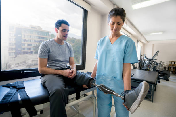 Disabled young man using a prosthetic and doing physiotherapy Disabled young man using a prosthetic and talking to a doctor while doing physiotherapy - healthcare and medicine prosthetic equipment photos stock pictures, royalty-free photos & images