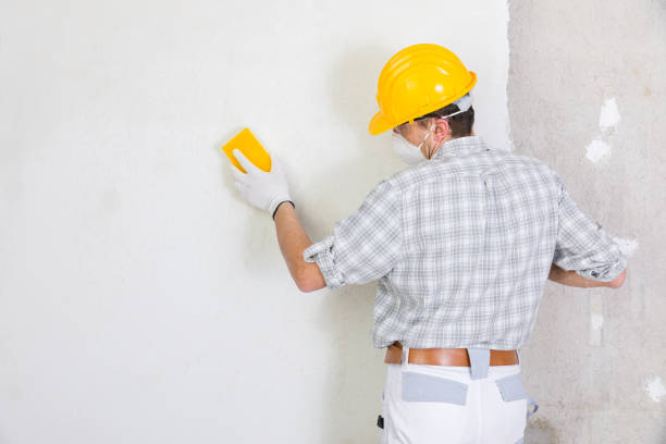 Builder sanding and smoothing newly plastered wall stock photo