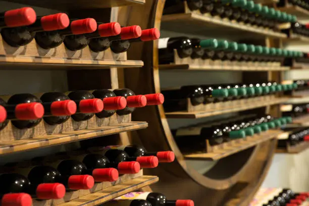 Selective focus of wine rack on wall in wood material full, to store red and white wine bottle in a row in cellar, cool and in good conditions.Some of those are old wine bottle with dust