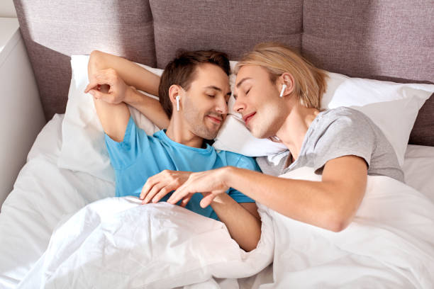 homosexual and same sex couple listening music in bedroom - sex and reproduction audio imagens e fotografias de stock