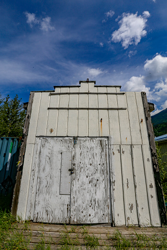 Facade of old garage with blue sky and clouds on background