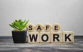 SAFE WORK - text on wooden cubes, green plant in black pot on a wooden background