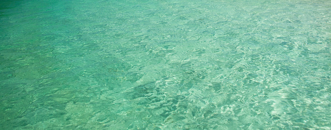 Sun illuminates shallow clear water as ripples of light dance on pristine turquoise sea creating a calming escape. Island of Borneo, Sabah State, Malaysia.