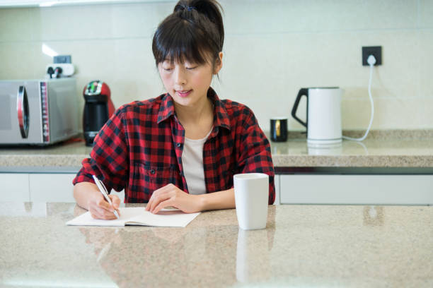 istock Woman writing list in the kitchen 1219475339