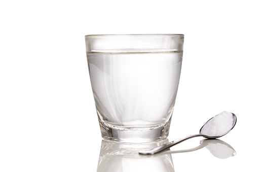 ORS or oral rehydration salt with glass of water and spoon with white background