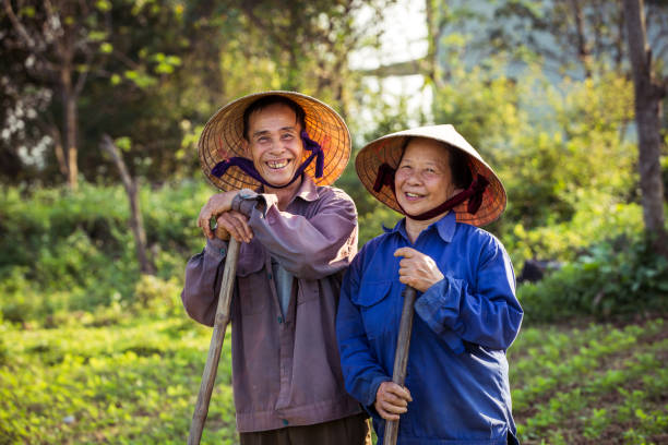 istock Smiling old Vietnamese couple on a farm with conical hats (non la) 1219476593