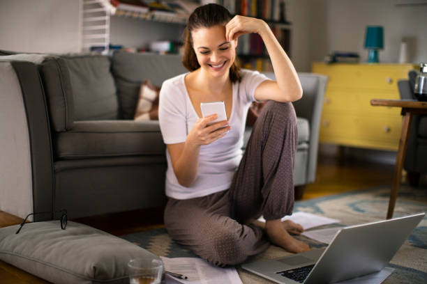 istock Young woman using a phone at home 1219480611