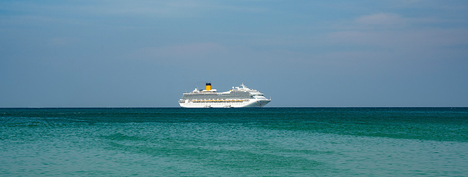 A Cruise ship seen in the middle of the Andaman Ocean near Patong Beach in Phuket, Thailand, during a hot summer day in the tropics.