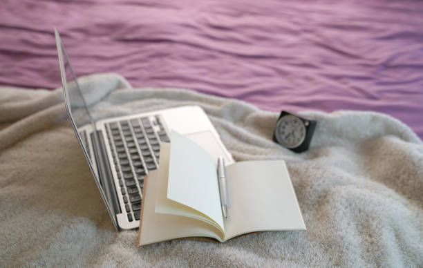 istock Notepad and computer laptop on top of bed. 1219487409