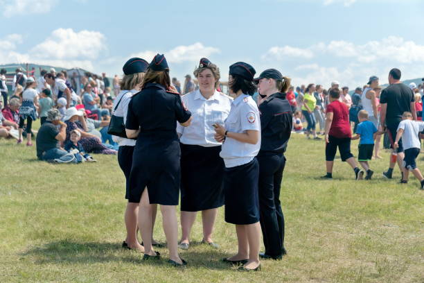 um grupo de mulheres com uniforme de polícia estão em uma clareira enquanto estão de plantão em meio a pessoas no festival de música e étnica karatag. - russian culture women spy russia - fotografias e filmes do acervo