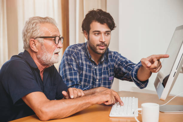 istock young man or son teaching his grandfather elderly dad learning to using computer at home. 1219494813