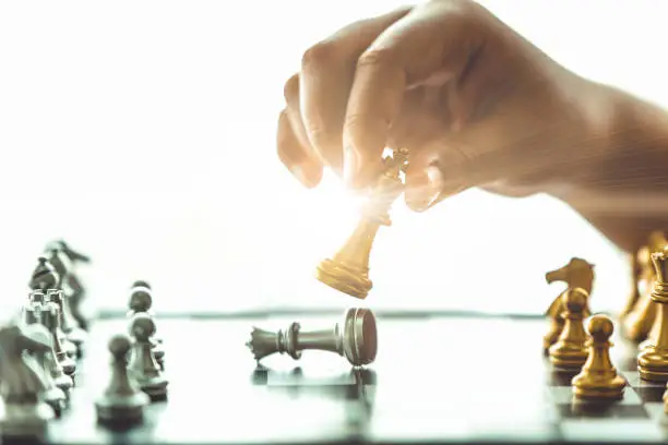 Closeup hand playing chess boardgame checkmate for win business concept.