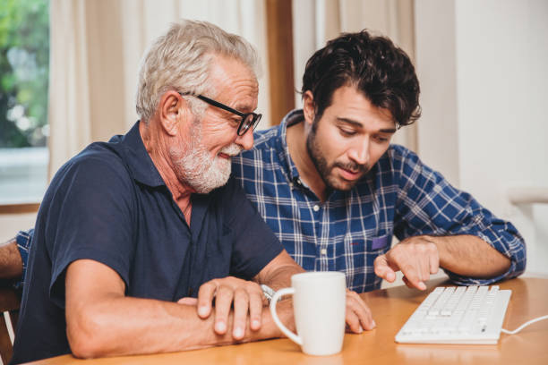 istock young man or son teaching his grandfather elderly dad learning to using computer at home. 1219496182