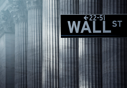 Wall Street sign post in front of Stock Exchange building in New York