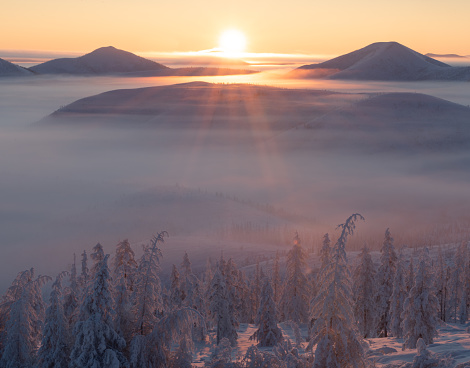 Beautiful sunrise over the mountains in foggy morning. Colorful winter landscape in mountains