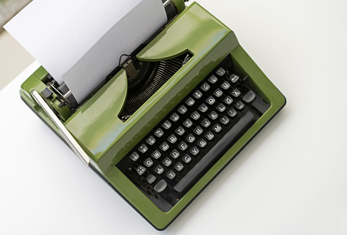 istock Old fashioned classic typewriter with sheet of paper on white wooden desk 1219497994