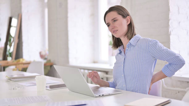 istock Tired Young Woman having Back Pain in Modern Office 1219498102